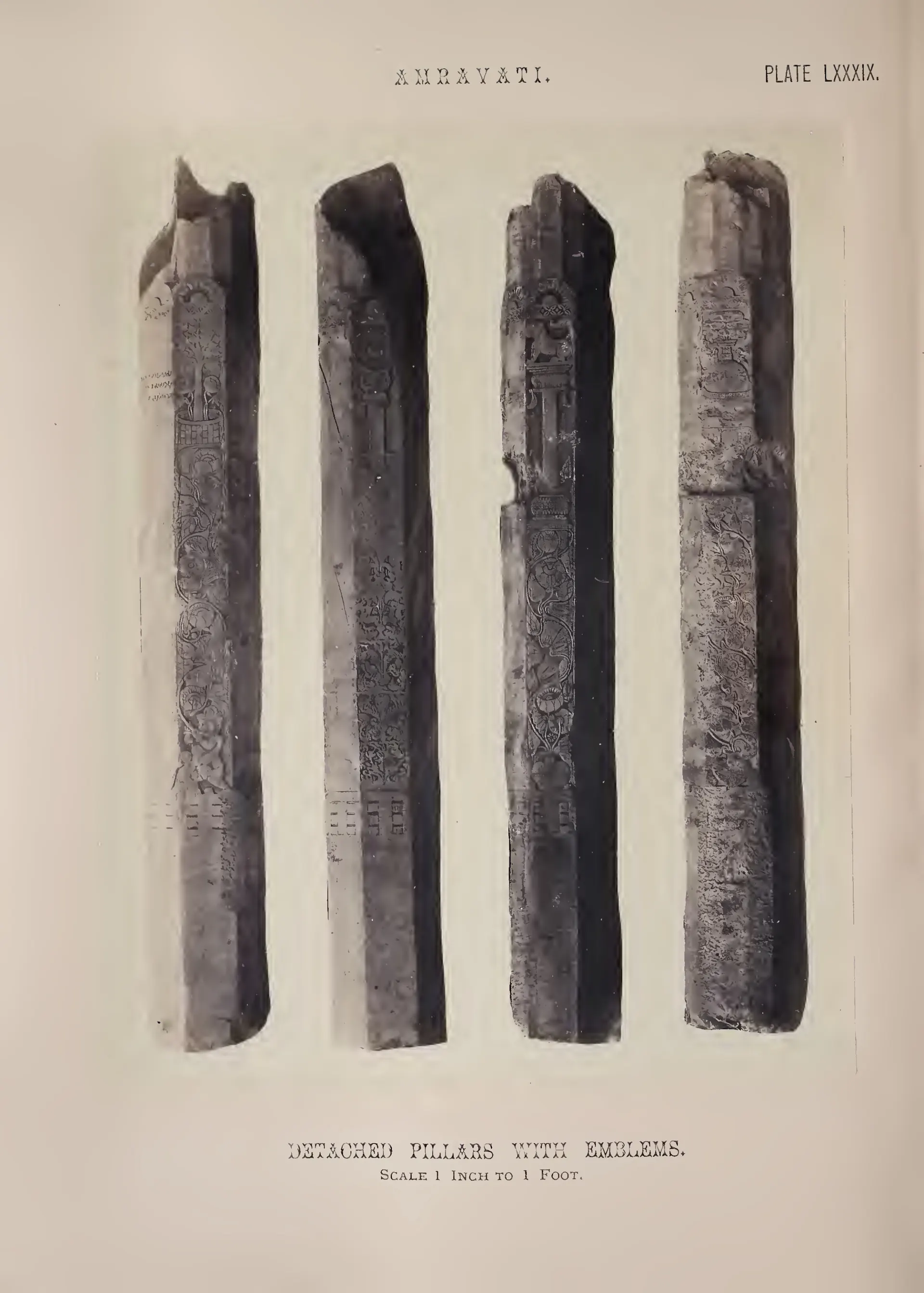 Photograph of four tall square pillars carved with emblems.