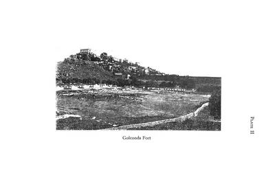Photograph of the fortified hill of Golconda seen across a plain, with a road curving towards it.