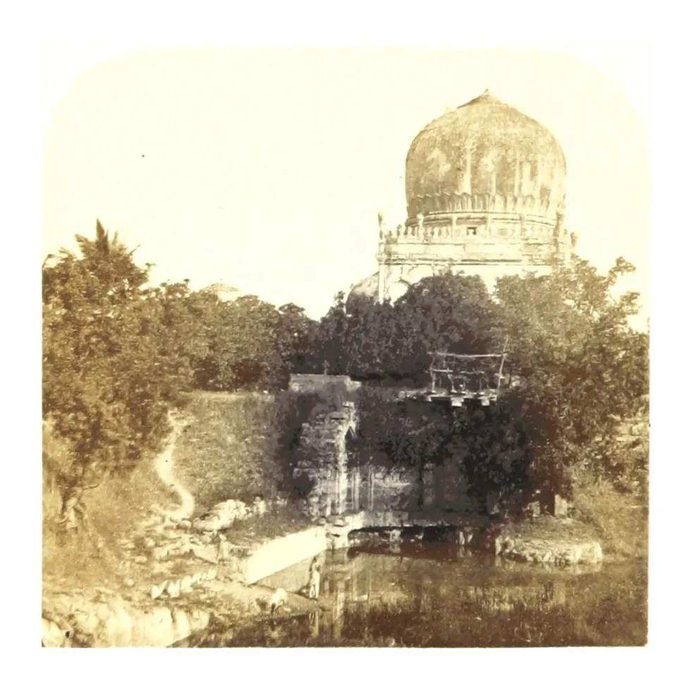 Old photograph of a large domed tomb rising behind trees and a stone tank.
