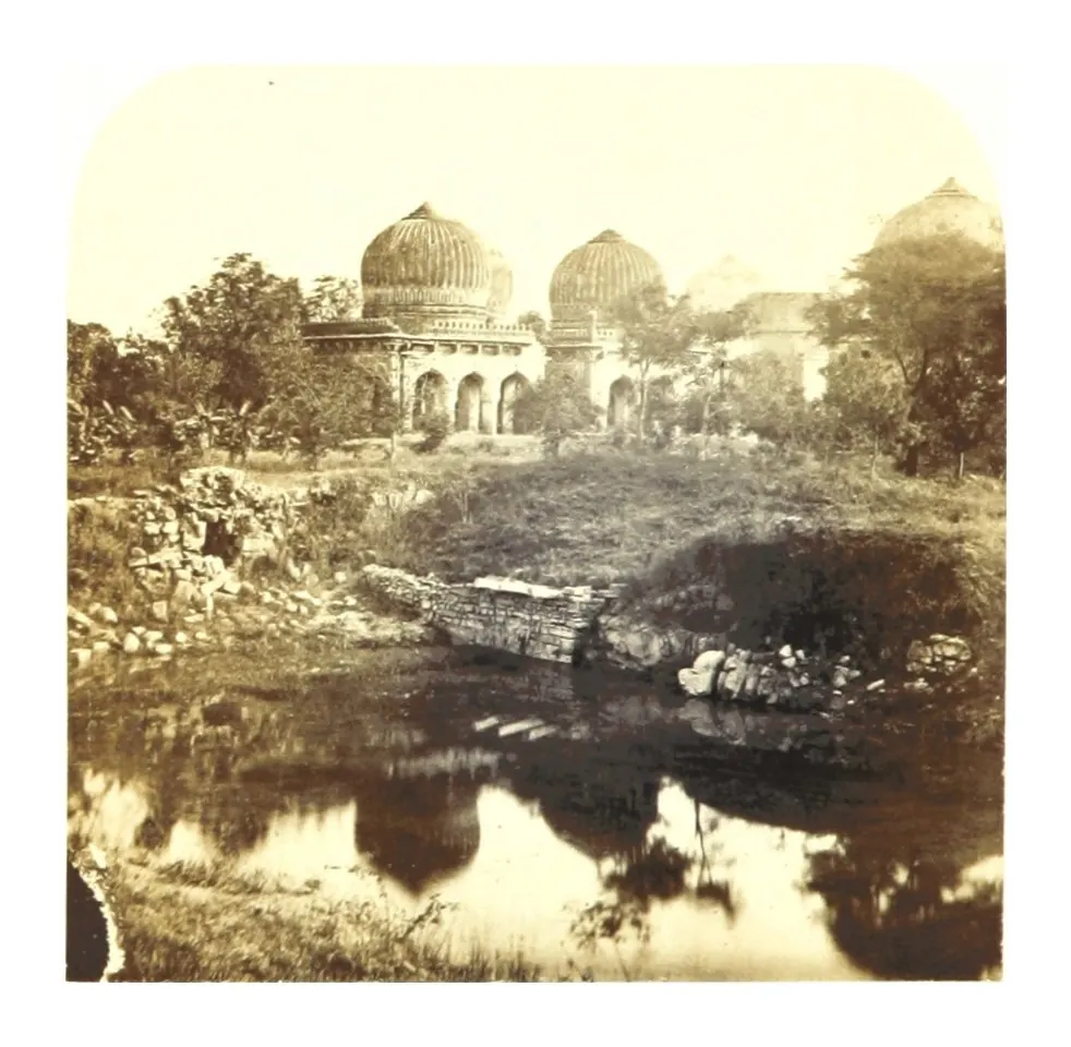 Old photograph of a group of domed tombs reflected in a pool, with trees around.