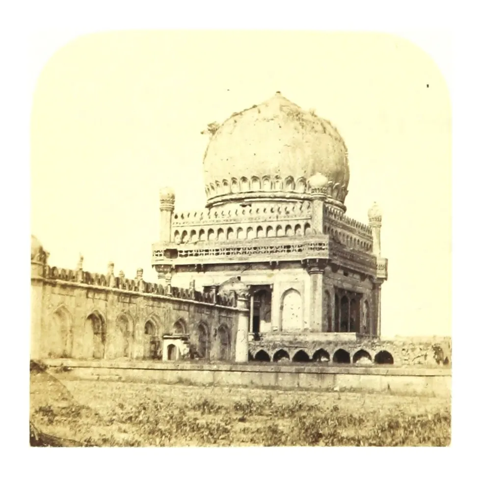 Old photograph of a large domed tomb on an arcaded base, seen beyond an enclosure wall.
