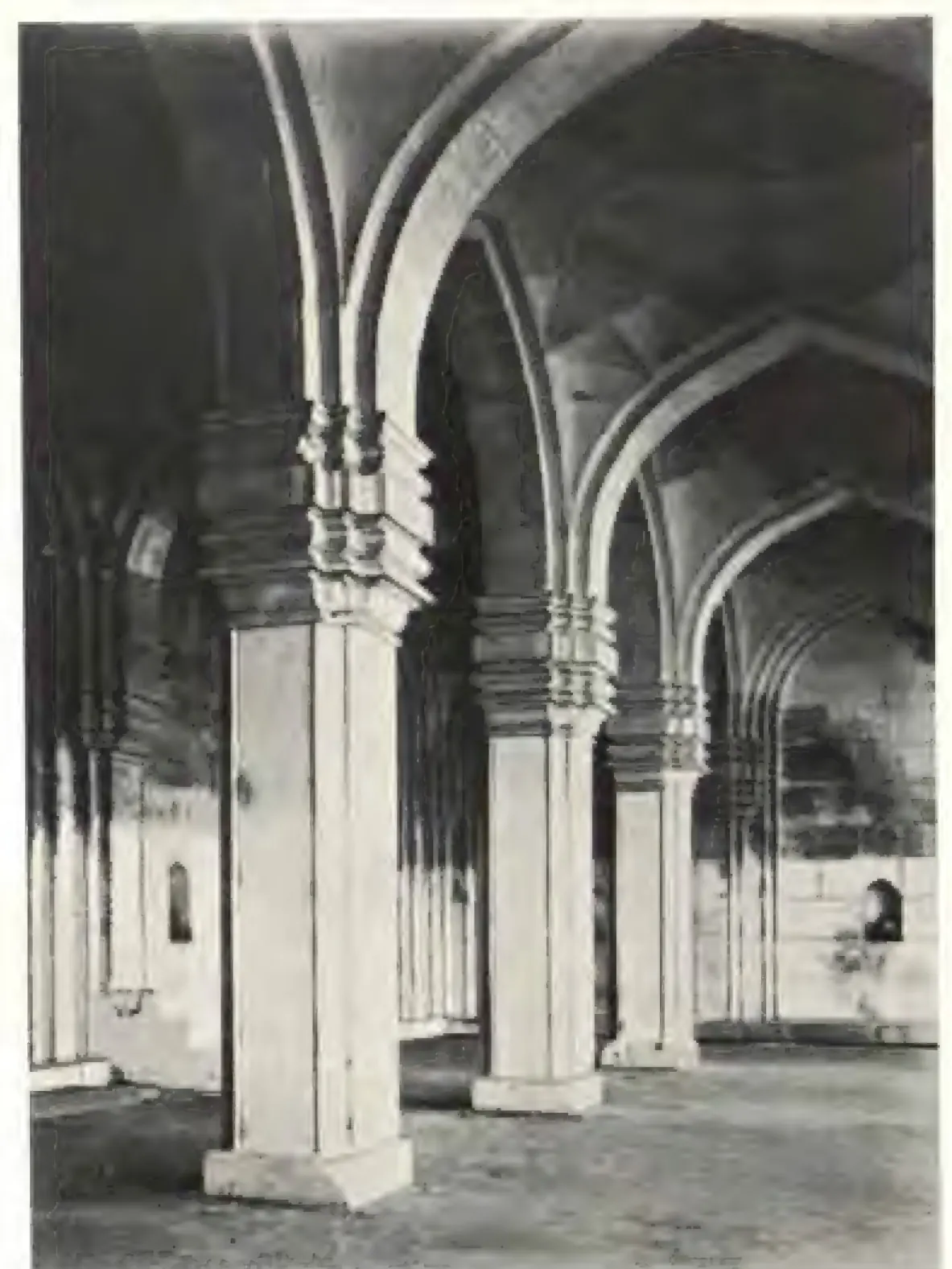 Photograph inside the prayer hall: tall clustered piers carrying pointed arches, with a niche in the far wall.