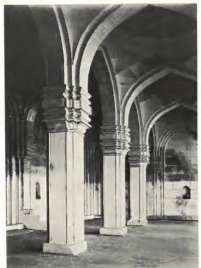 Photograph inside the prayer hall: tall clustered piers carrying pointed arches, with a niche in the far wall.
