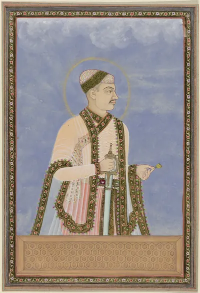 Deccani painting of a standing ruler in a pink robe with a long patterned coat, a small cap and a halo, against a blue ground in a decorated border.