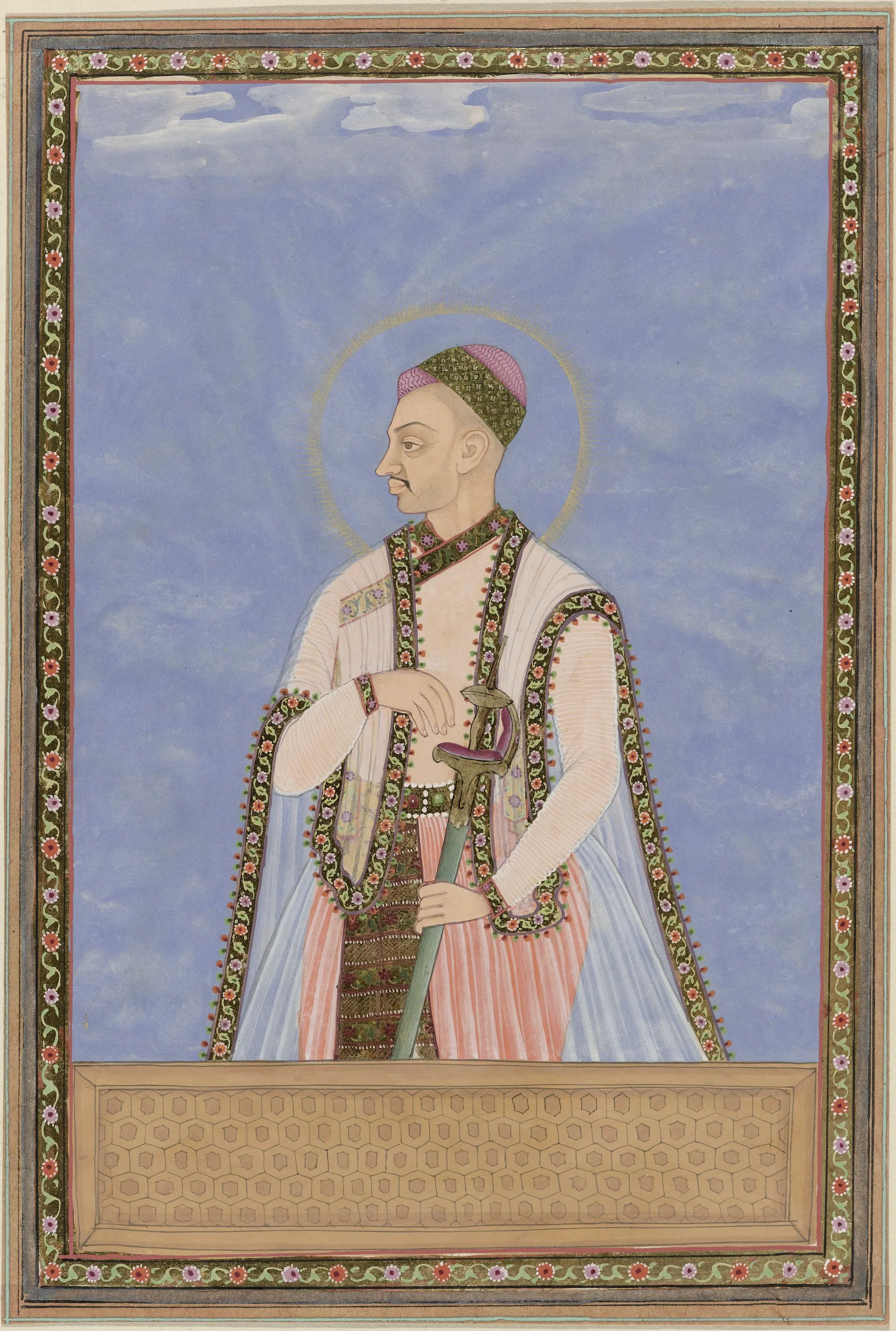 Deccani painting of a standing ruler in a white robe and patterned coat with a halo, against a blue ground in a decorated border.