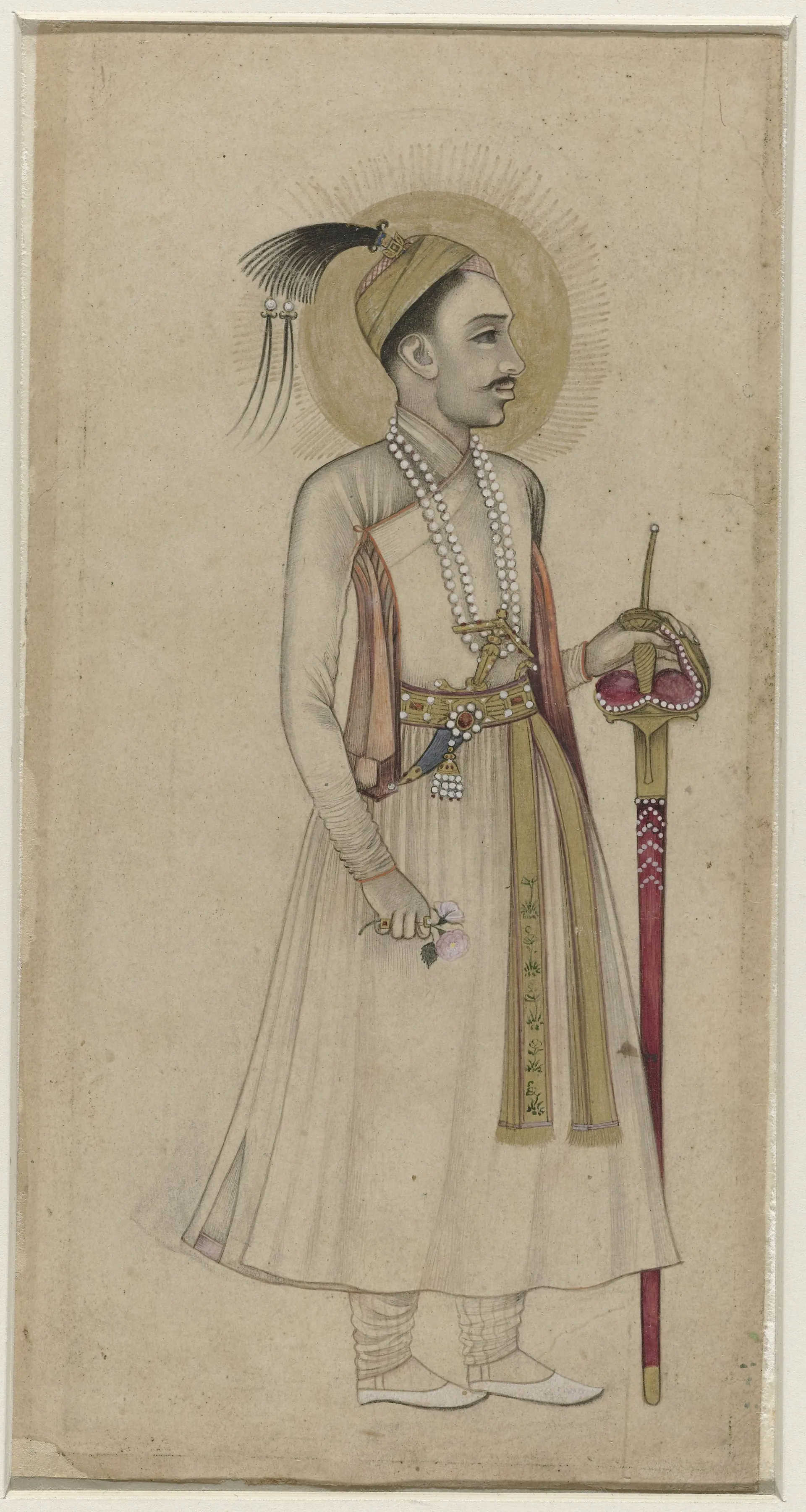 Deccani drawing, lightly coloured, of a standing man in a long white robe and plumed turban holding a sheathed sword, on a plain ground without a border.