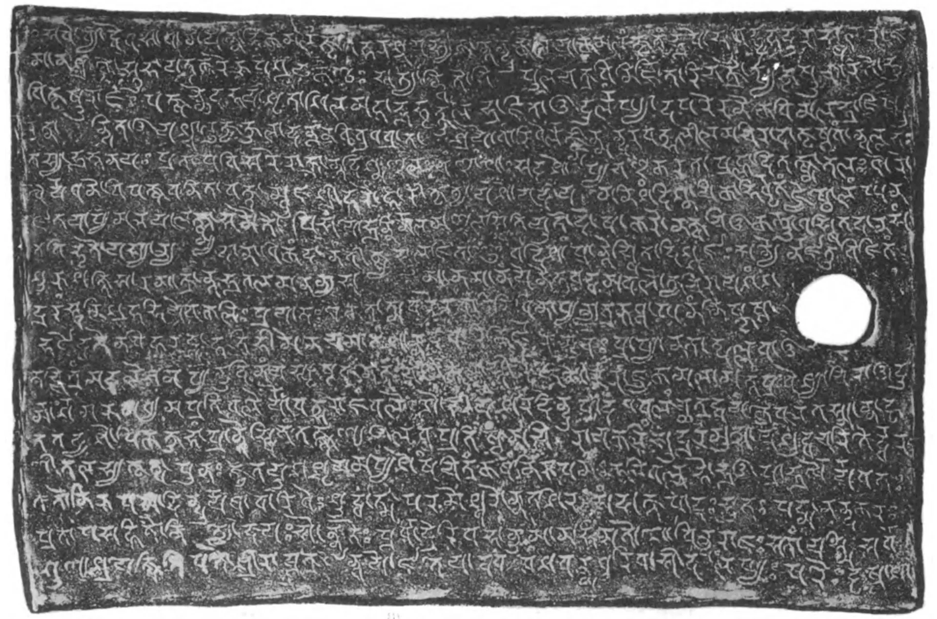 Collotype of one side of an inscribed copper plate, grey, densely written Sanskrit in Nagari letters, lines 1–18, with a ring hole.