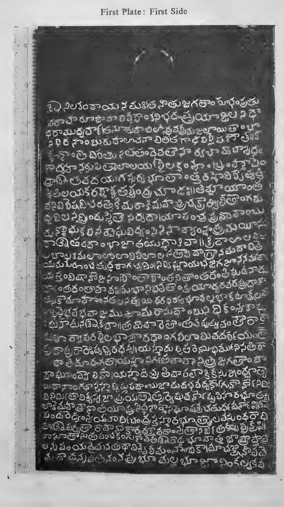 Photograph of one inscribed copper-plate face, upright and narrow, about thirty lines of light Telugu letters on the dark metal, with a raised rim and the ring hole at one end; line numbers printed in the margin.