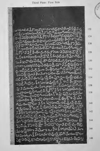 Photograph of one inscribed copper-plate face, upright and narrow, about thirty lines of light Telugu letters on the dark metal, with a raised rim and the ring hole at one end; line numbers printed in the margin.