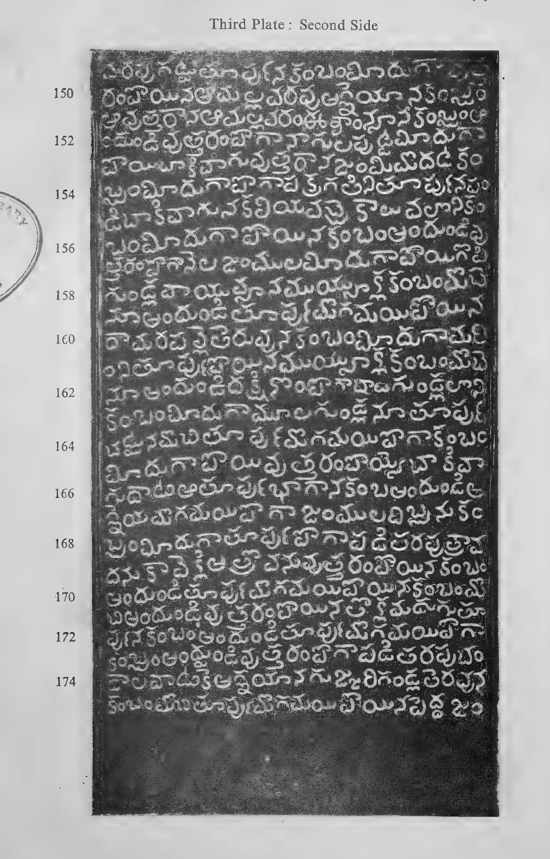 Photograph of one inscribed copper-plate face, upright and narrow, about thirty lines of light Telugu letters on the dark metal, with a raised rim and the ring hole at one end; line numbers printed in the margin.
