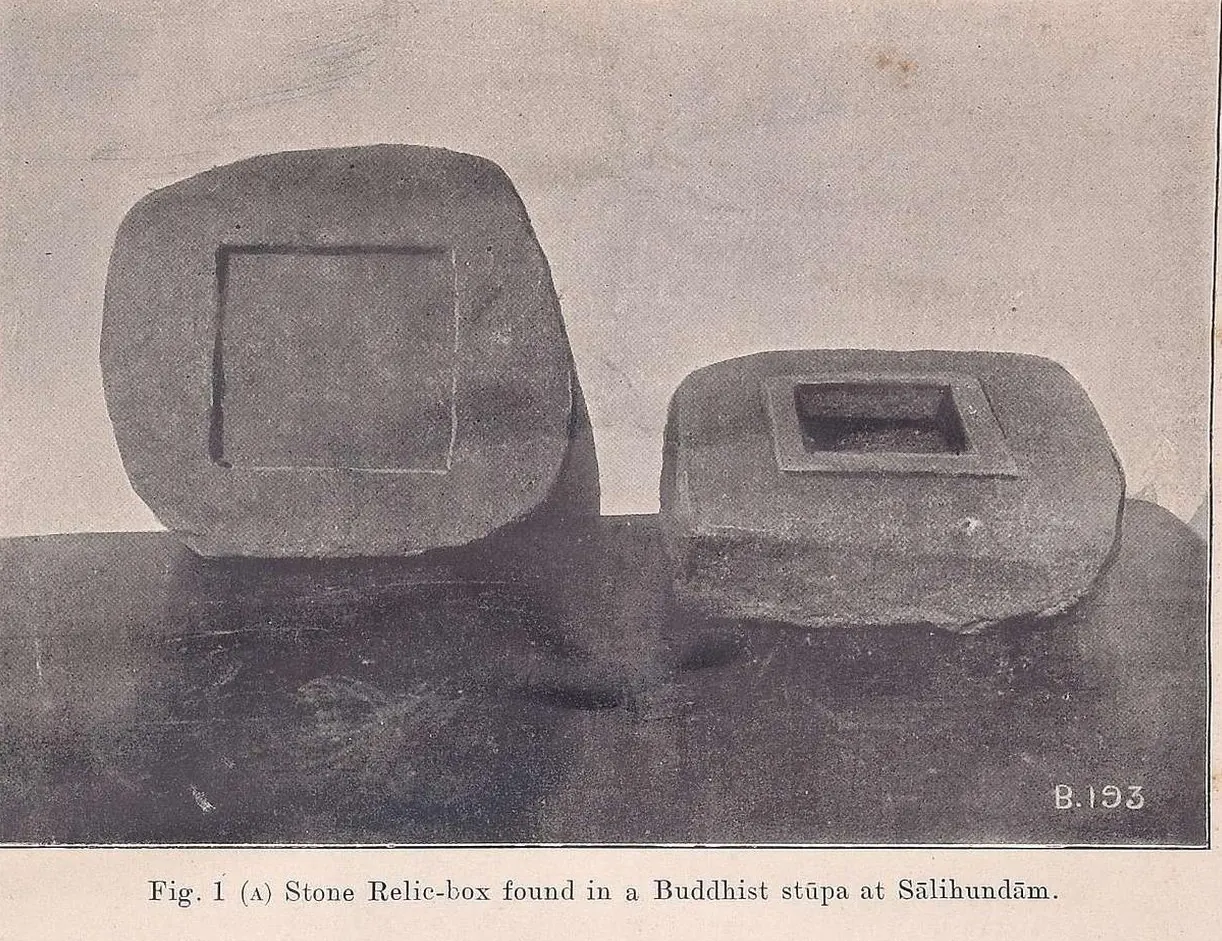 Photograph of a rough granite block with a small square cavity and raised rim, beside its slab lid with a square sunk panel on its underside, standing on a dark surface.
