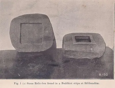 Photograph of a rough granite block with a small square cavity and raised rim, beside its slab lid with a square sunk panel on its underside, standing on a dark surface.