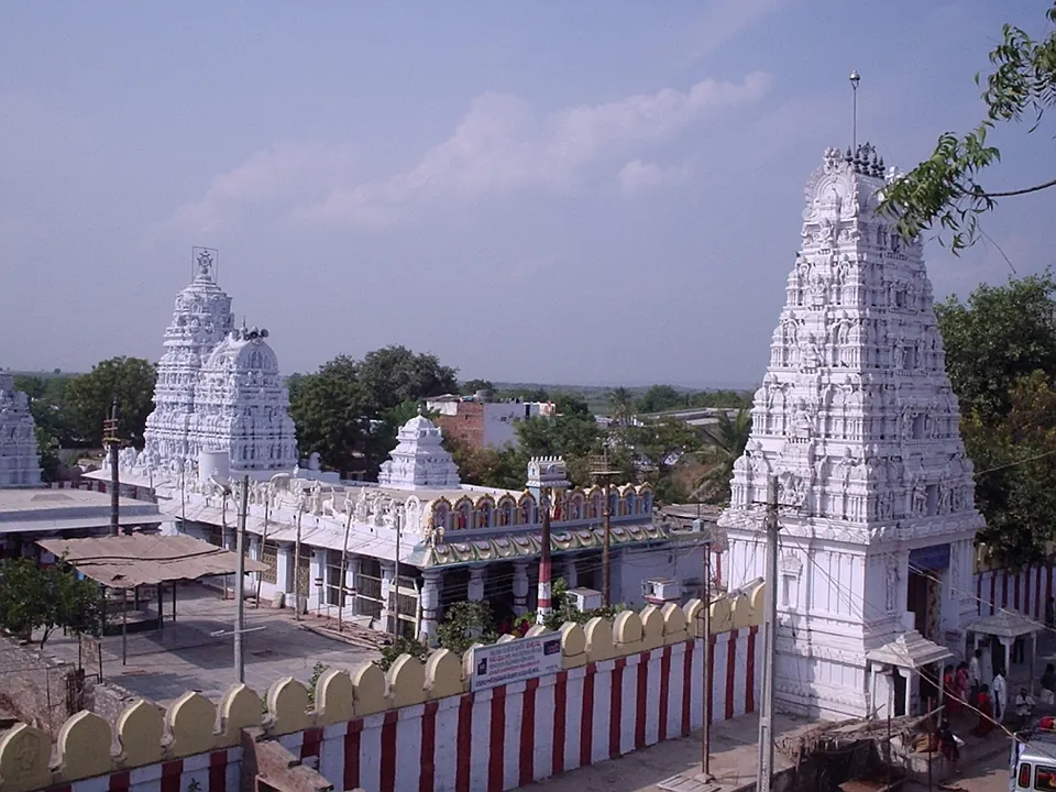 Whitewashed temple compound with a tall gateway tower on the right and a cluster of smaller towers behind a crenellated wall.
