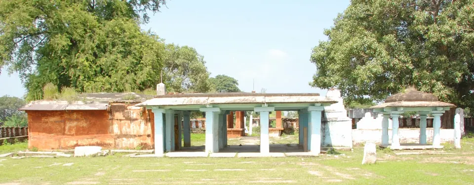 A low open pillared hall with a flat roof and smaller shrines on a grassy compound under large trees.