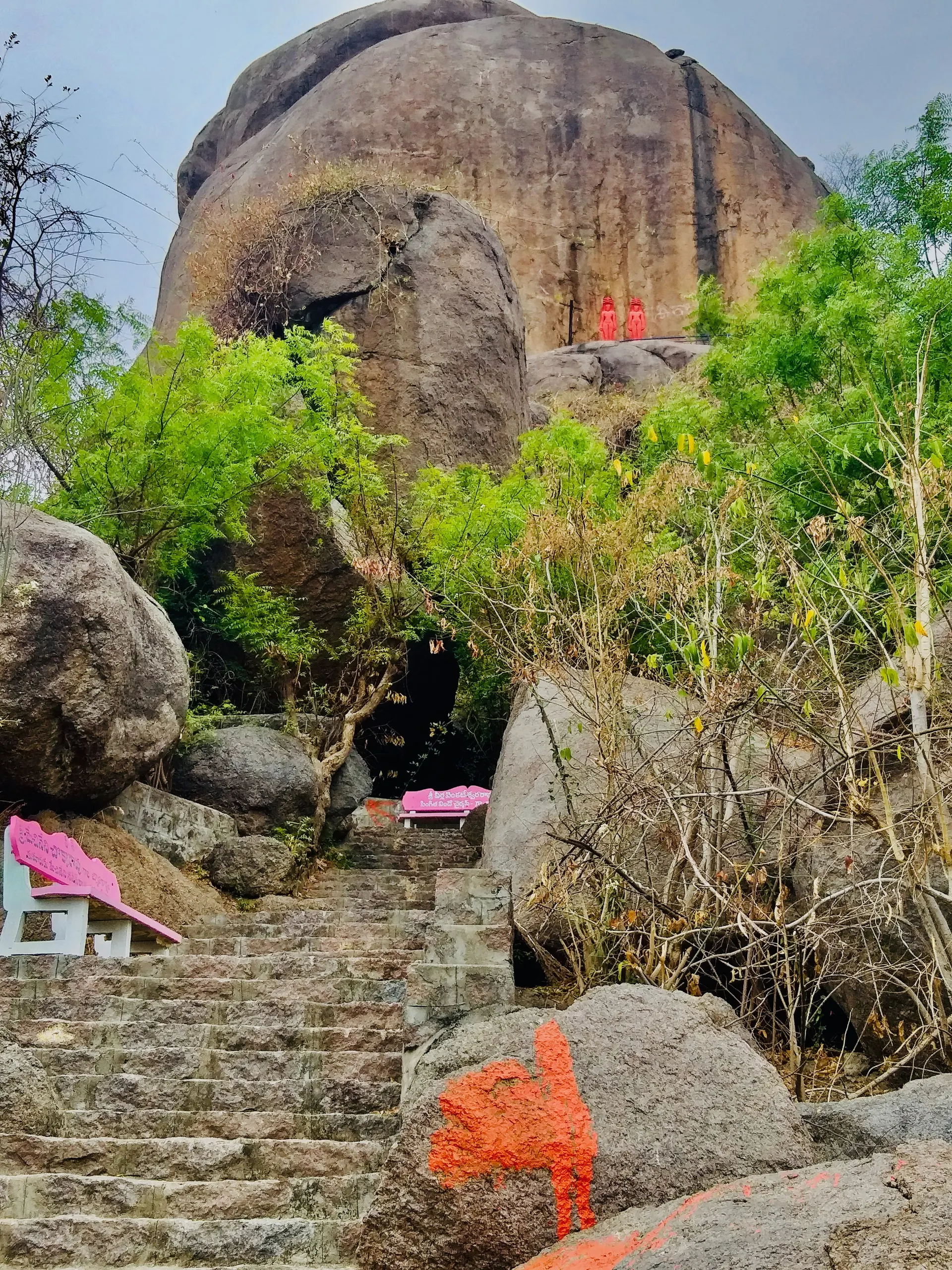 The Bommala Gutta at Kurikyal: a hill of piled granite boulders under a blue sky, with modern stone steps climbing between shrubs towards the top.