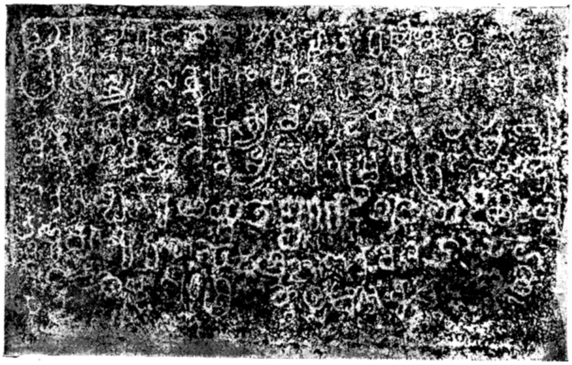 Ink impression of a short inscription of eight lines in early Telugu-Kannada letters, white on a mottled black ground, wider than it is tall.