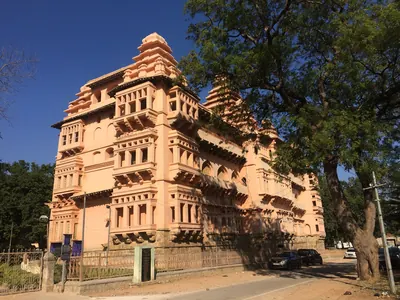 Colour photograph of the restored three-storeyed palace at Chandragiri with arched balconies and stepped towers, trees at right.