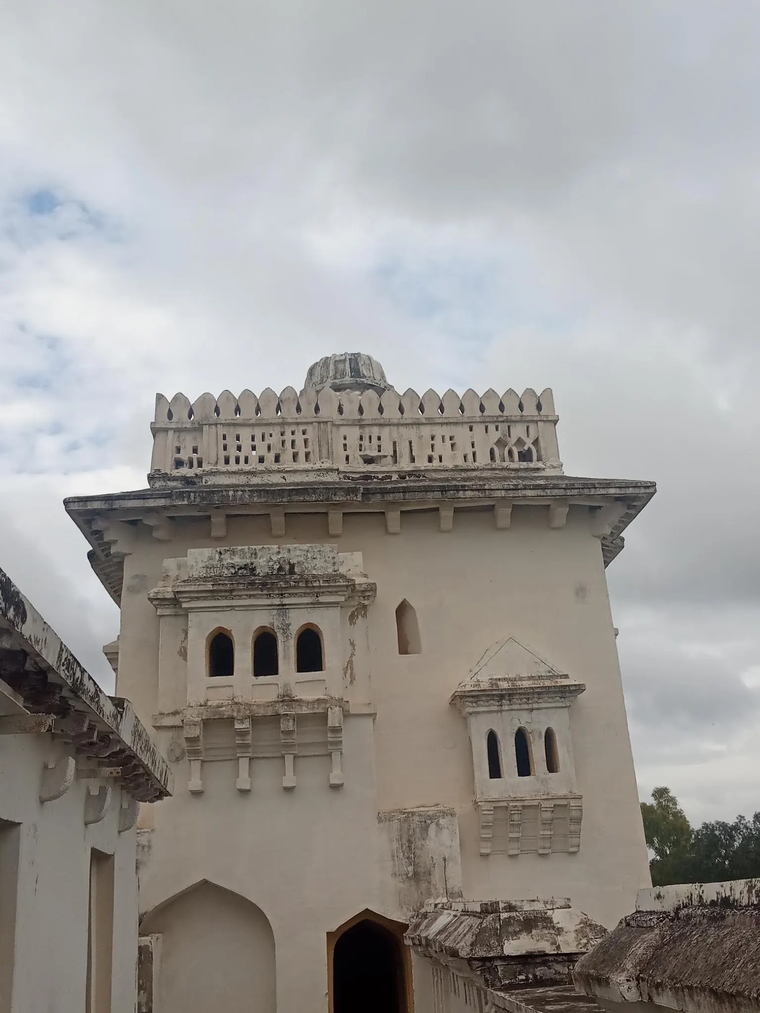 Colour photograph of a whitewashed two-storeyed palace building with arched windows and a crenellated square tower.