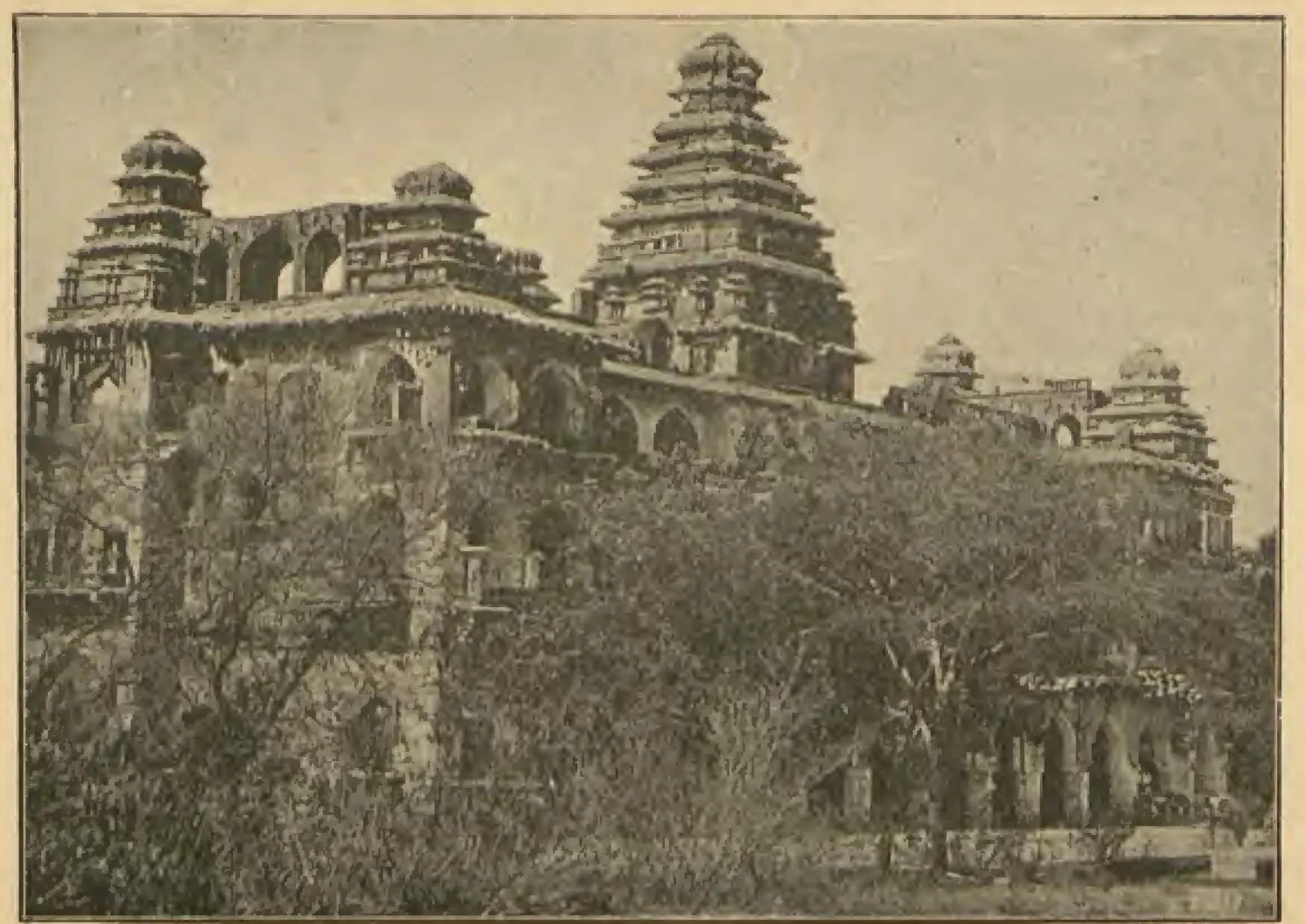 Photograph of the three-storeyed Raja Mahal at Chandragiri, its long arcaded facade topped by stepped towers, the largest in the centre, with trees in front. Printed sideways on the page.