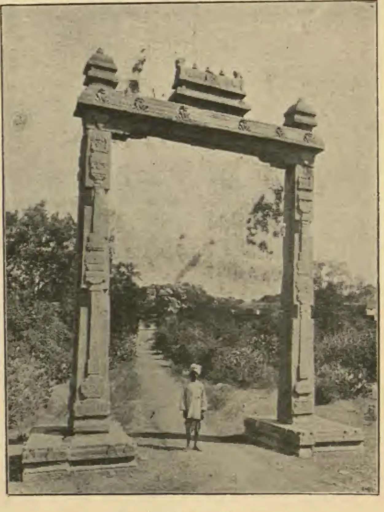 Photograph of a tall stone gateway-like frame of two pillars and a carved lintel standing in open ground, the balance from which kings were weighed against gold.